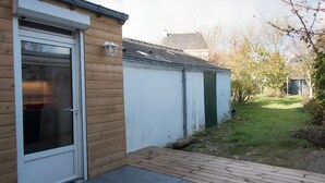 Ett trähus med en vit dörr och en liten veranda.