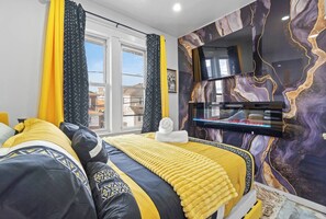 A bedroom with a bed, curtains, a TV, and a marble wall. - VIP LUX-2 Bedroom Apart-15 min NYC-Shared Parking (Fairview)