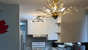 Una cucina moderna con mobili bianchi, zoccolo nero in piastrelle e piano cottura in acciaio inossidabile.