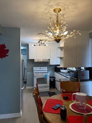 A modern kitchen with white cabinets, a black tiled backsplash, and a stainless steel stove. - StayMaple: Cozy ski retreat on Copper Mountain w/artist studio. Pet-Friendly! (Toronto)
