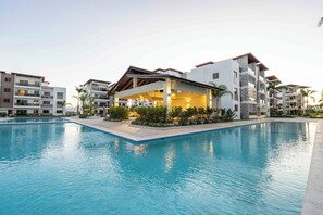 Um hotel moderno com piscina, várias varandas e área externa coberta.