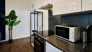 A modern kitchen with a black induction cooktop, a white microwave, and a black oven. - En déplacement, Wifi, 10 minutes de la gare (Tourcoing)