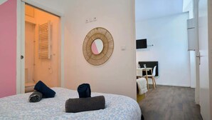 Une chambre avec un lit, un miroir fixé au mur et une petite table avec une chaise.