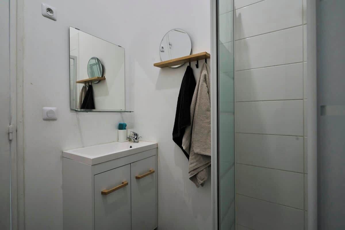 Une salle de bain avec un lavabo blanc, un miroir et un porte-serviettes.