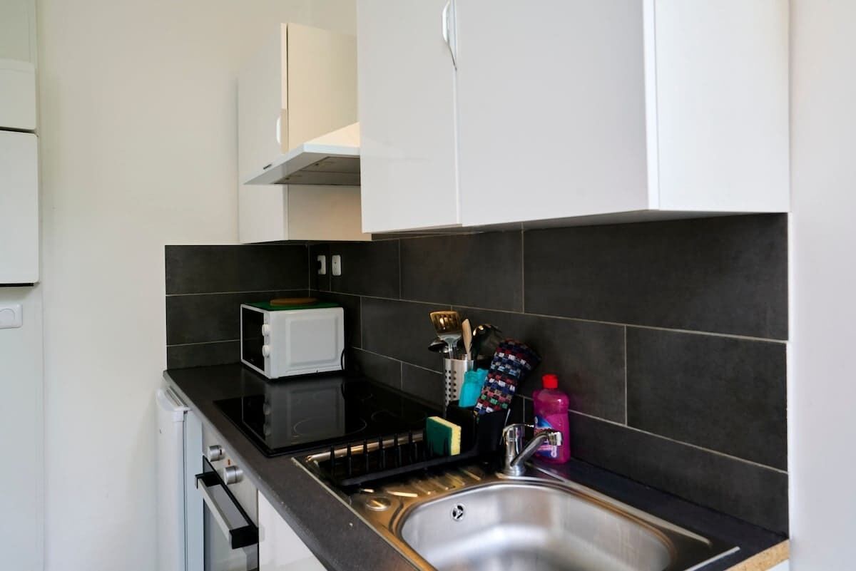 A modern kitchen with a black countertop, stainless steel sink, and white cabinets.