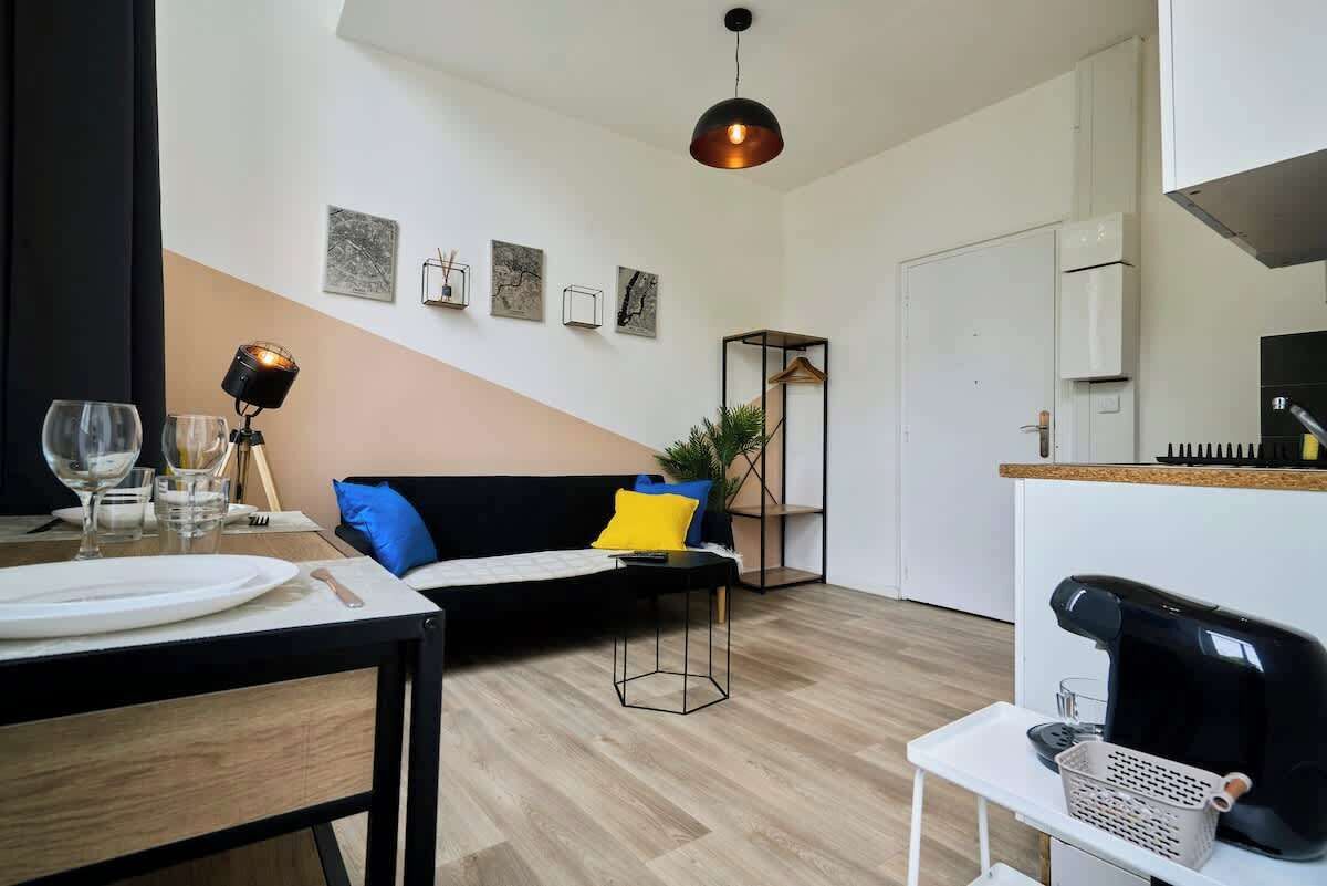 Un soggiorno moderno con zona pranzo, un divano con cuscini, un lampadario e opere d'arte alle pareti.