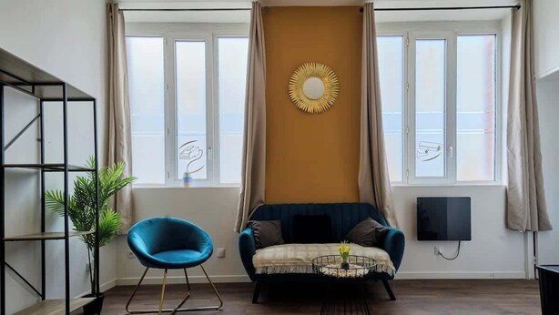 Un soggiorno moderno con una poltrona blu, un divano, un tavolino da caffè e un elemento decorativo a parete.