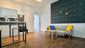 A modern kitchen with a dining area, a sofa with cushions, and a patterned wall. - Modern Apt, Fast WiFi, Near Tourcoing Train (Tourcoing)