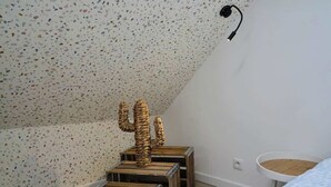 A room with a speckled ceiling, a wooden cactus sculpture, and a round wicker basket on a small table. - En déplacement 9, Dernier étage, wifi gratuit (Tourcoing)