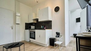 A modern kitchen with white cabinets, a black countertop, and a coffee machine. - Modern Apt Near Tourcoing Sta. w/ Fast WiFi (Tourcoing)