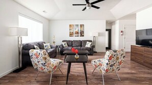 A modern living room with a ceiling fan, two sofas, a coffee table, and a TV. - Canyon View Central Location Workspace Garage (Grand Junction)
