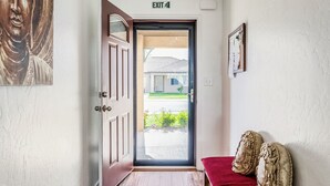 A hallway with a wooden floor, a red bench, a Buddha statue, and an exit sign. - Canyon View Central Location Workspace Garage (Grand Junction)