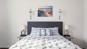 A bedroom with a large bed, two bedside tables with lamps, a framed picture on the wall, and a dark headboard. - Canyon View Central Location Workspace Garage (Grand Junction)