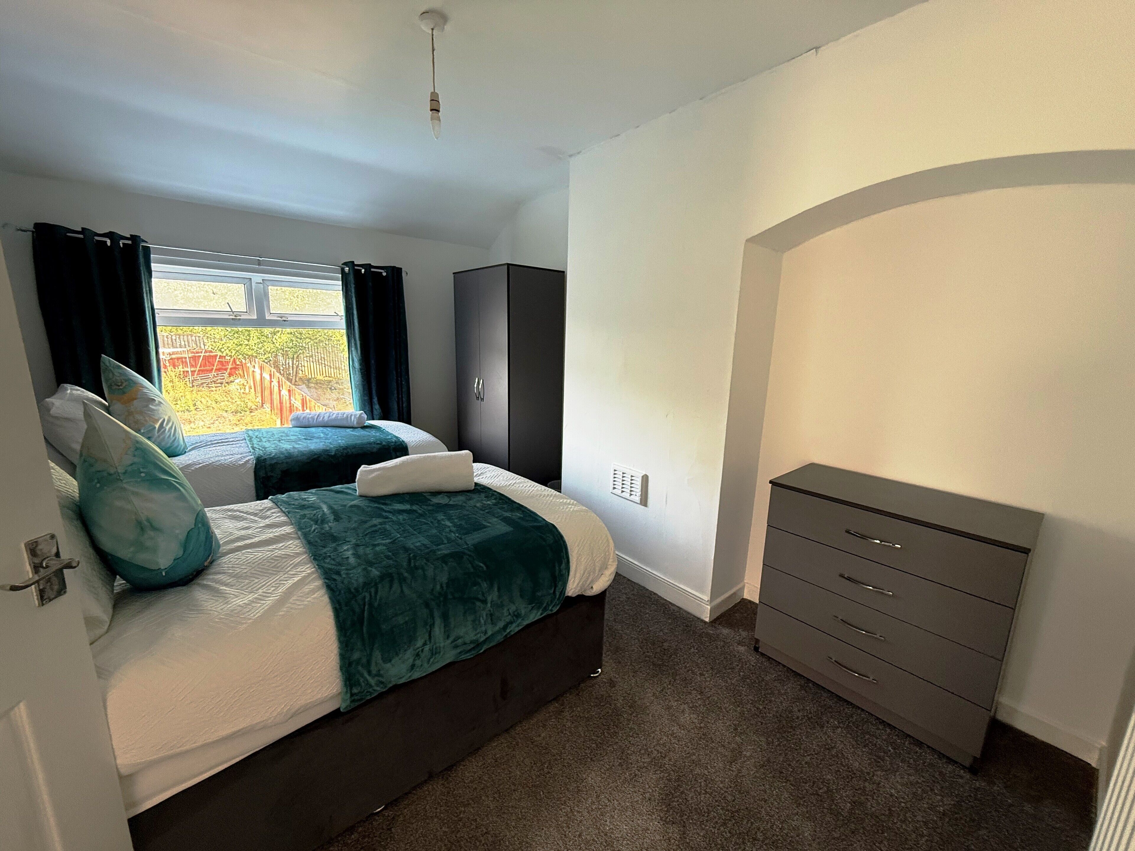 Un dormitorio con dos camas, un armario y vistas al exterior.