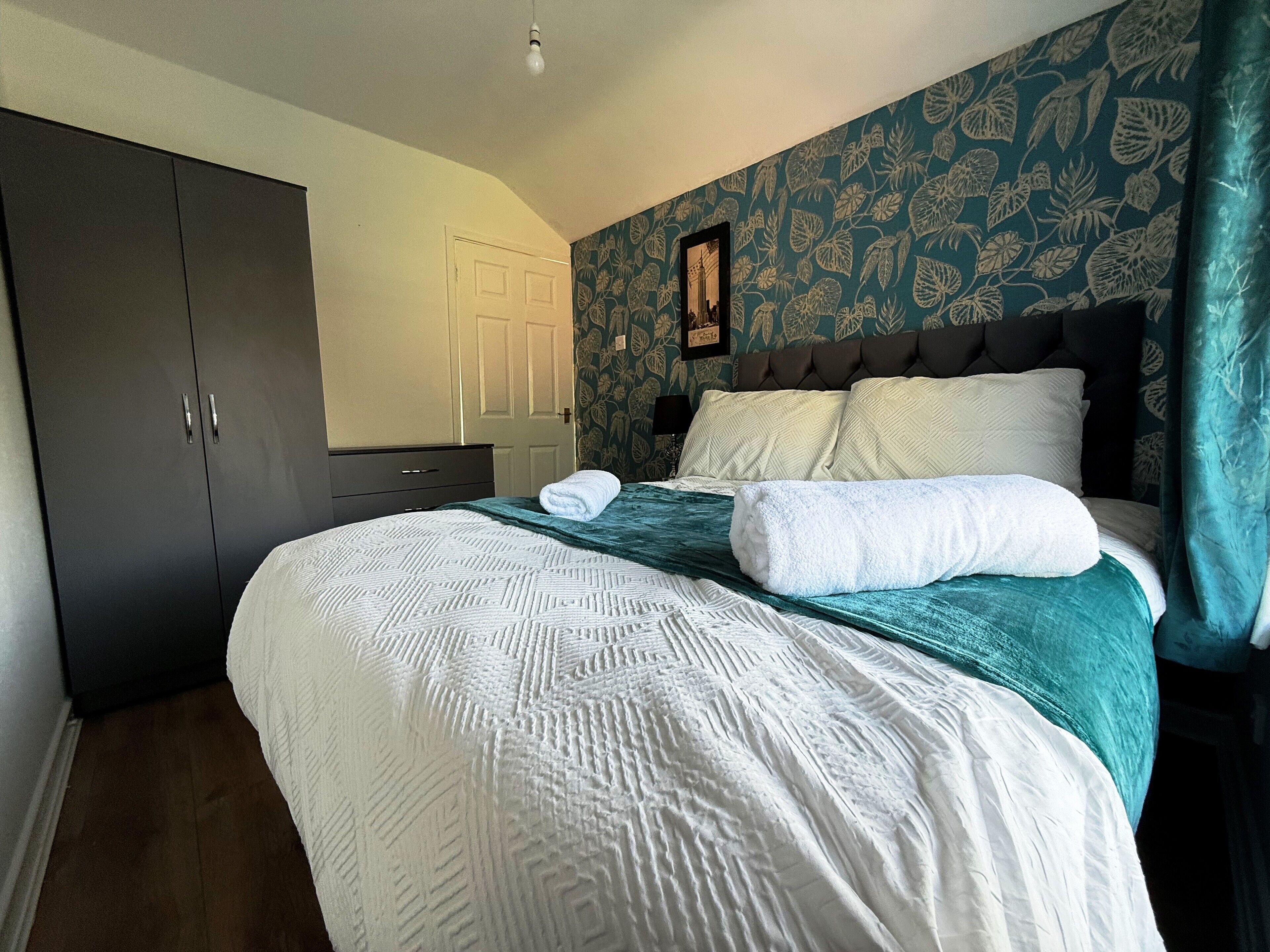 Un dormitorio con cama, armario, puerta y pared con diseño.