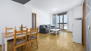Een moderne woonkamer met een eethoek, een grijze bank, een witte salontafel en een groot raam met uitzicht.