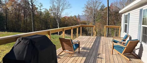 Una terraza de madera con mobiliario exterior y una parrilla.