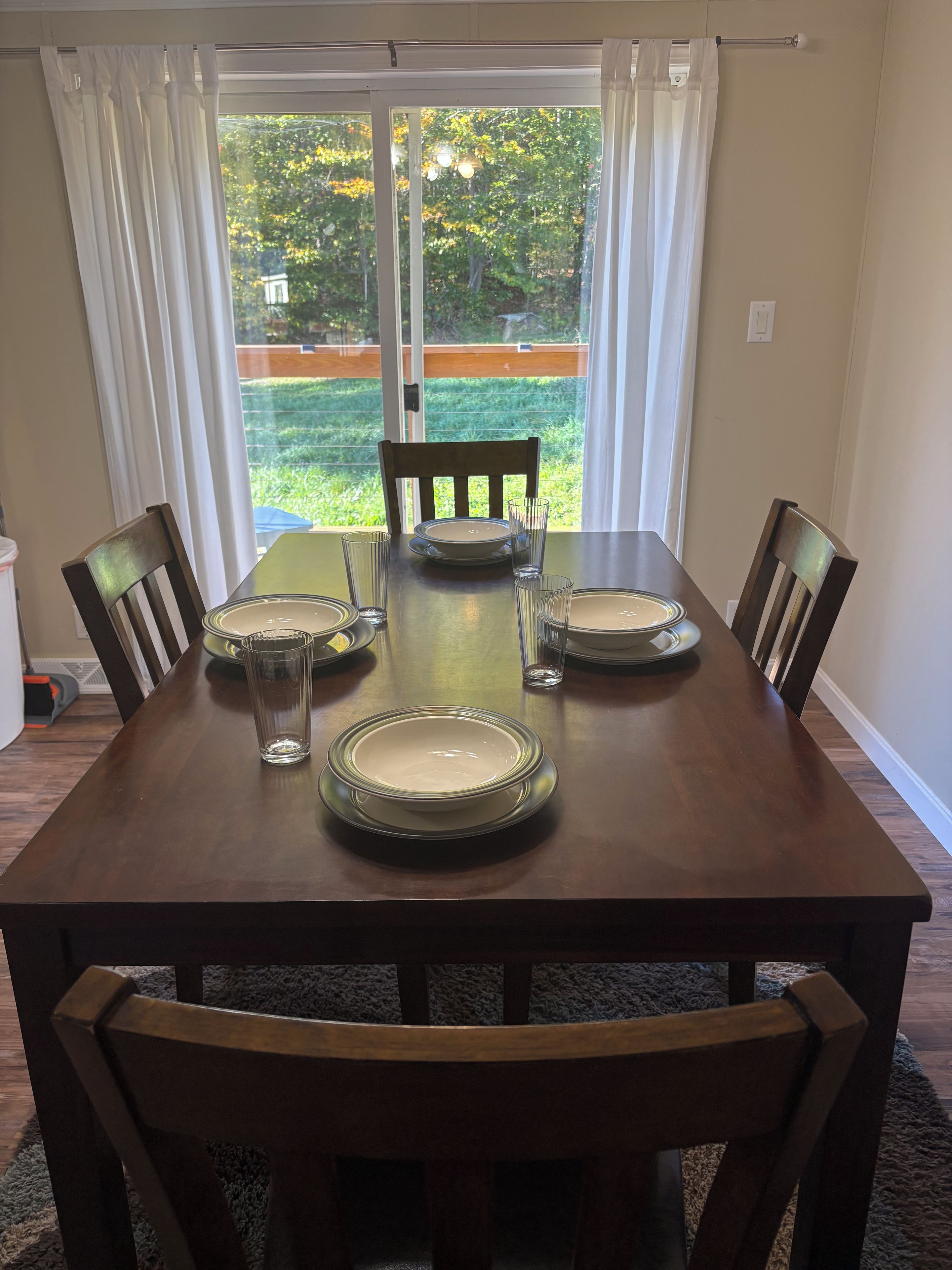 A dining table set for four with chairs, a glass of water, and plates.
