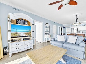 Ein Wohnzimmer mit Fernseher, Couch, Holztisch und Deckenventilator.