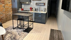 A modern kitchen with a central island, stainless steel appliances, and a brick accent wall. - Cozy 1-bedroom apartment in brilliant Cincinnati with AC (Cincinnati)