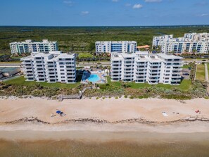 Ein Strandhotel mit mehreren Gebäuden, einem Schwimmbad und einem Strandabschnitt.
