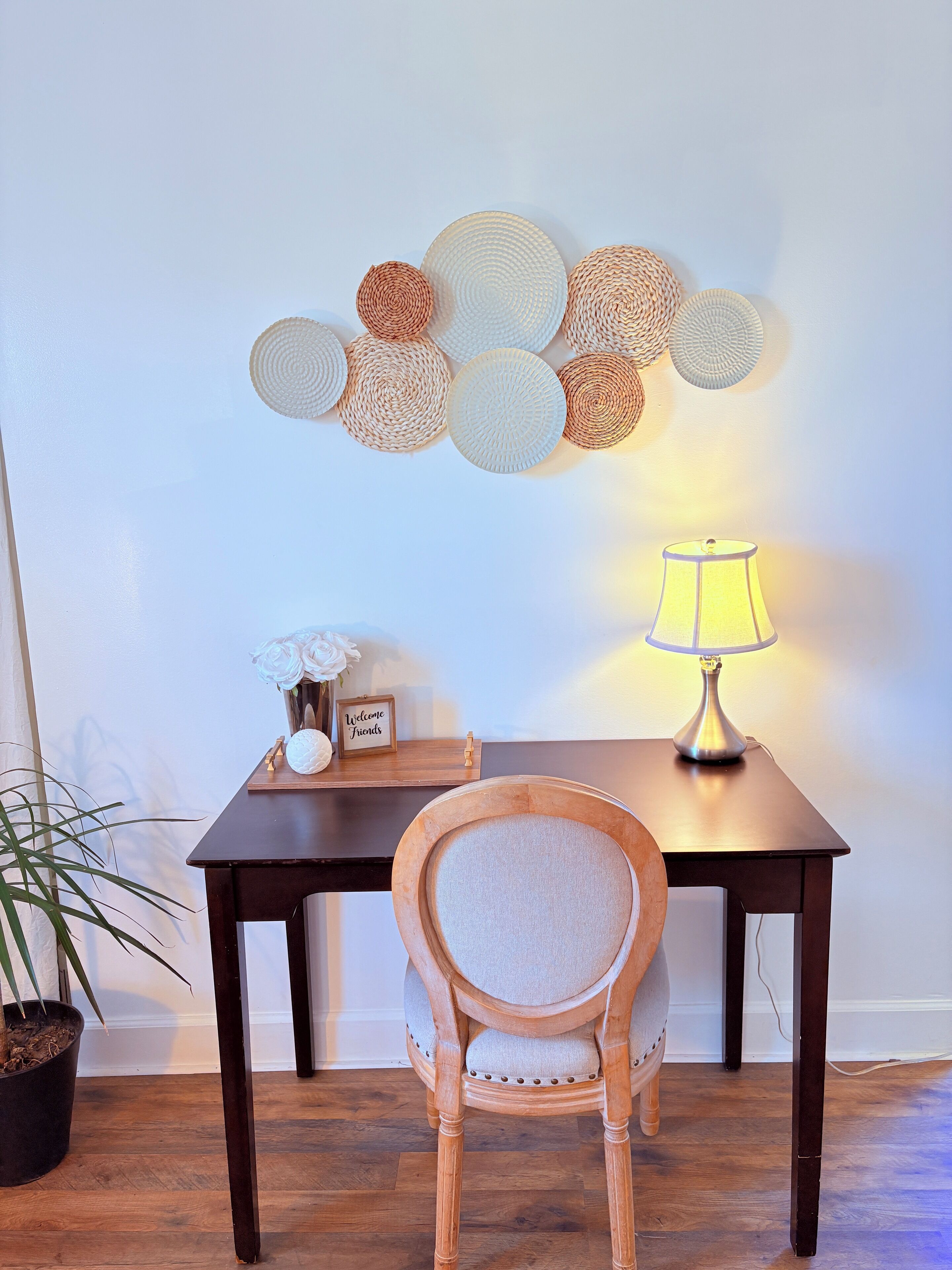 Une table à manger en bois, avec une lampe, une chaise, une plante en pot et un élément décoratif mural.