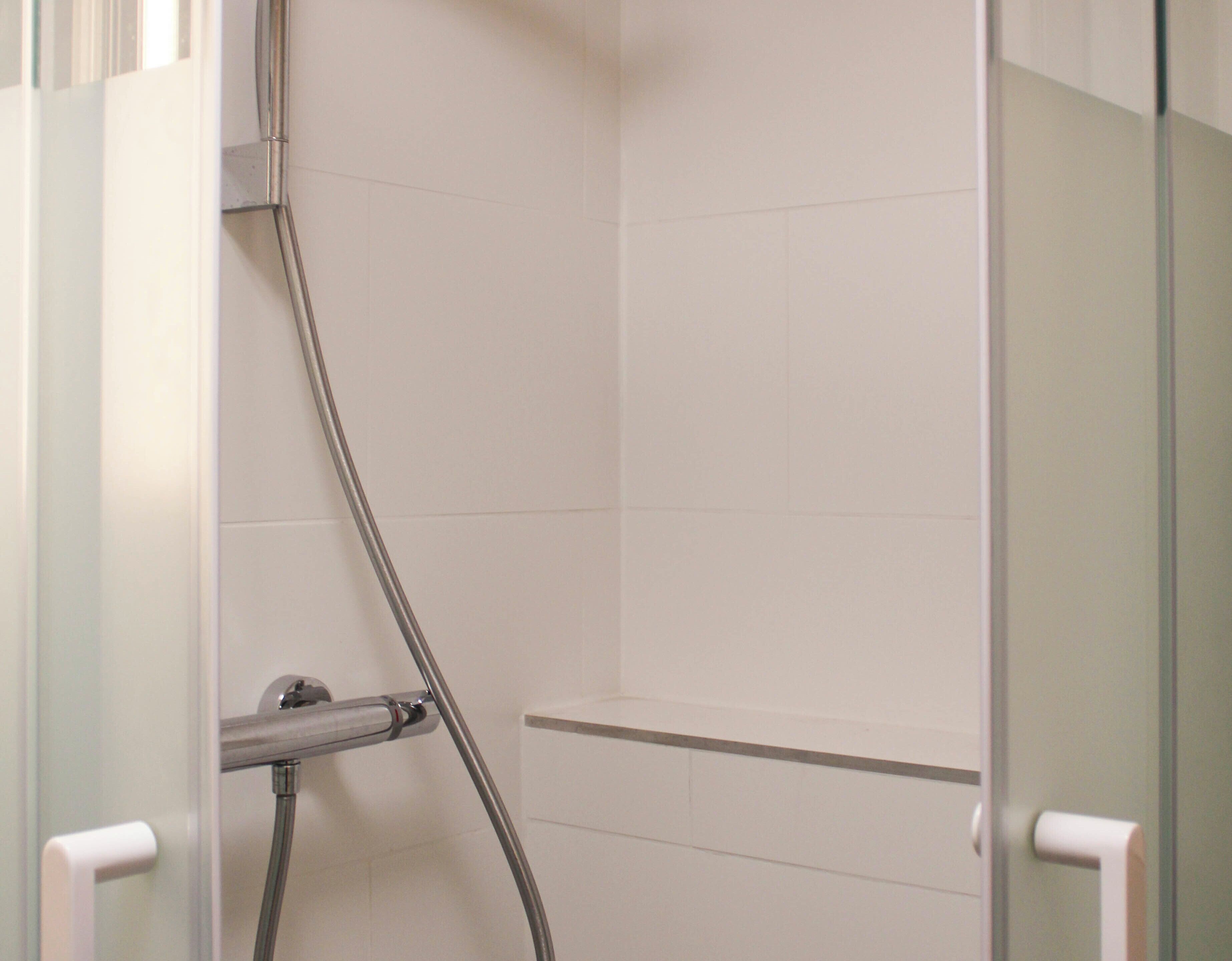 A shower with a glass door and a metal showerhead.