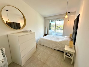 A bedroom with a bed, a dresser, a mirror, and a balcony with a view. - Cozy apartment with terrace in Cannes (Cannes)