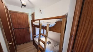 Una cama litera con escalera, una puerta de madera y un aplique en el techo.