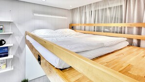 A bunk bed with a wooden frame, a desk with a chair, and a shelf with books.