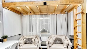 A room with two beige sofas, a white desk, and a wooden ladder.
