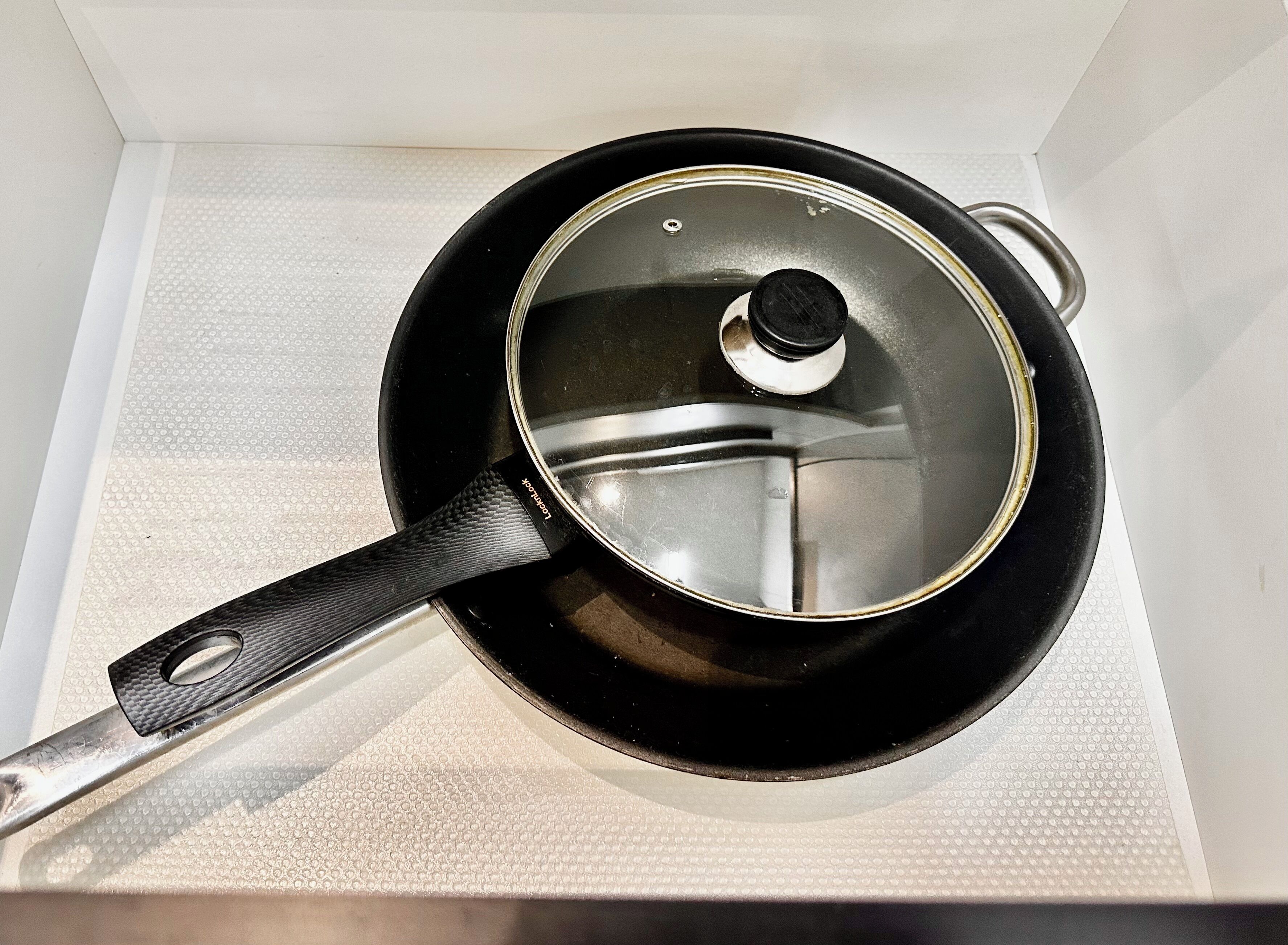 A black frying pan with a textured handle resting on a white surface.