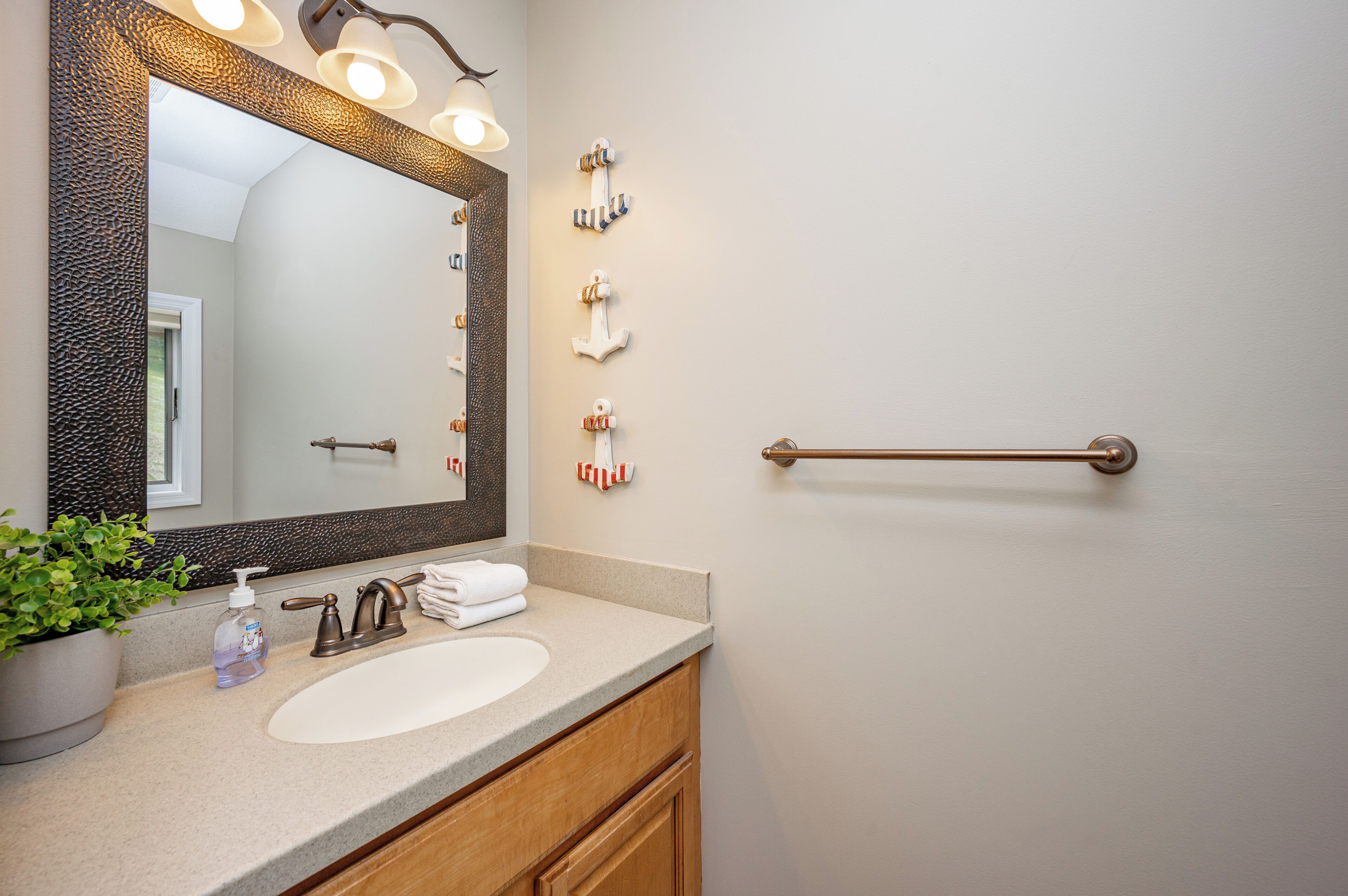 A bathroom with a large mirror, a sink, a towel rack, and a towel dispenser.