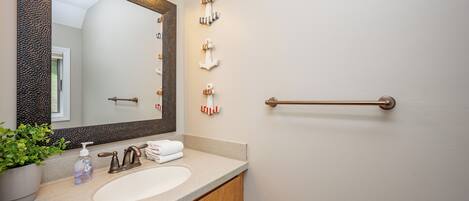 A bathroom with a large mirror, a sink, a towel rack, and a towel dispenser.