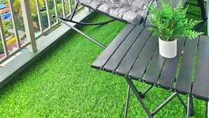A balcony with a cushioned chair, a small table, and a potted plant. - Condo in Davao City - 2BR Penthouse @ Verdon Parc (Davao City)