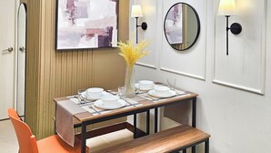 A modern dining area with a wooden table set for two, a bench, and a vase with dried plants. - Condo in Davao City - 2BR Penthouse @ Verdon Parc (Davao City)