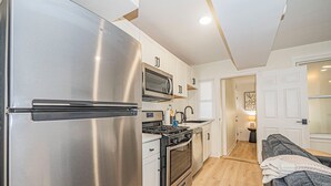 Una cocina compacta con refrigerador, microondas y horno de acero inoxidable.