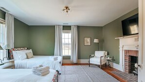 Ein Hotelzimmer mit zwei Betten, einem Kamin, einem Fernseher und einem Fenster mit Vorhängen.