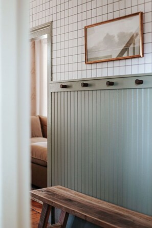 Une pièce avec un banc en bois, un cadre photo accroché au mur et un radiateur.