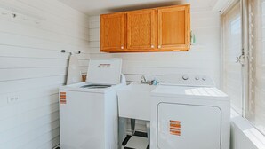 Une buanderie équipée de deux machines à laver, d’un sèche-linge et de placards en bois situés au-dessus.