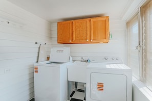 A laundry room with two washing machines, a dryer, and wooden cabinets above. - Barrel Sauna, Hot Tub & Views (Roseland)