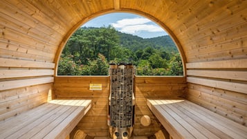 Una sauna con bancos de madera y vistas a una ladera boscosa.