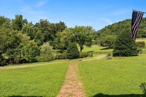 A grassy pathway leading to a building with a flag. - Barrel Sauna, Hot Tub & Views (Roseland)