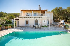 Ein zweistöckiges Haus mit Swimmingpool, Gartenmöbeln und einem Garten.