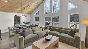 Ein geräumiges Wohnzimmer mit hoher Decke, großen Fenstern und einer gemütlichen Sitzecke.