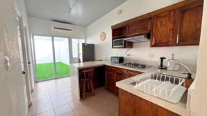A kitchen with wooden cabinets, a microwave, a stove, and a sink with a dish rack.