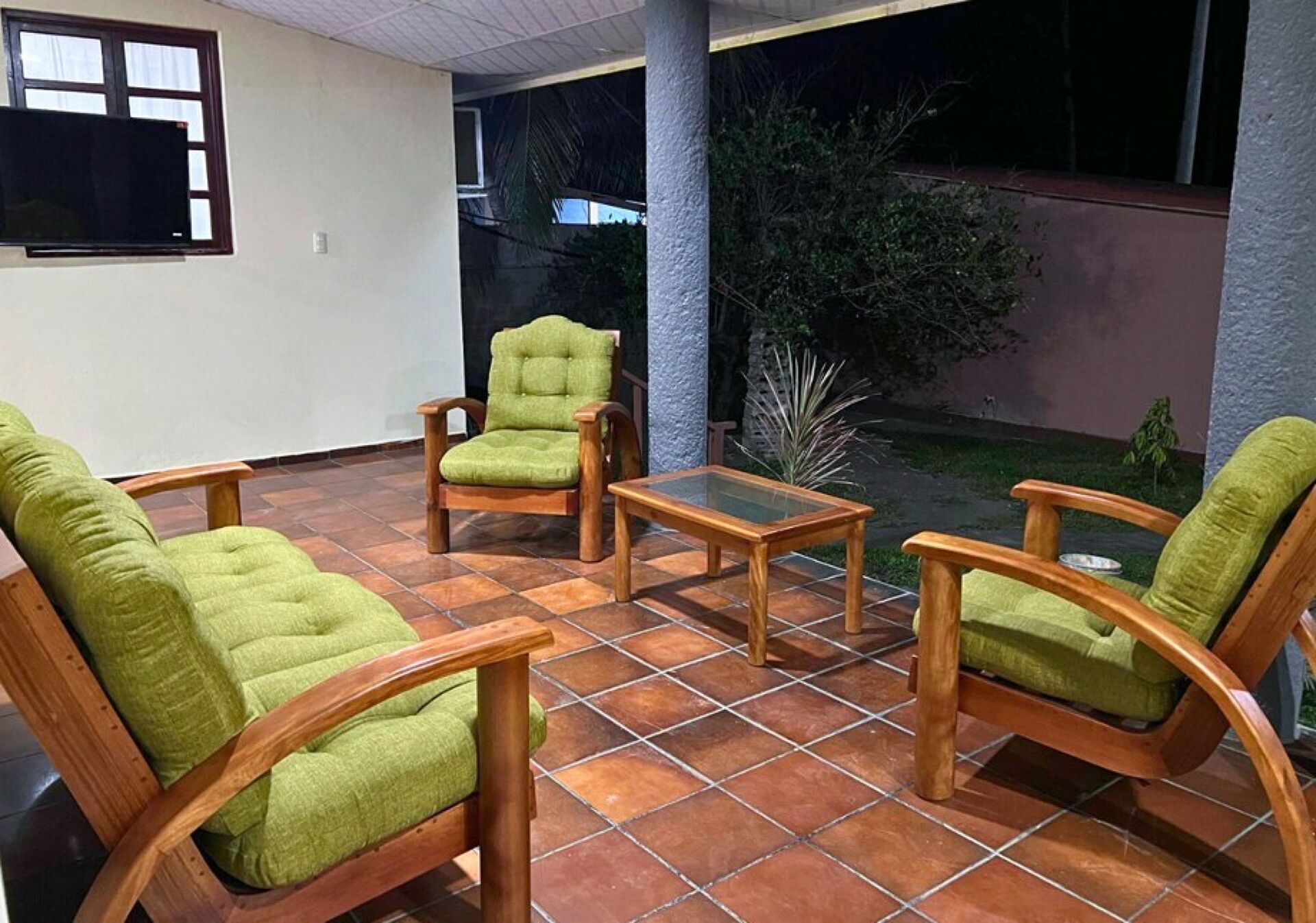 A patio area with wooden furniture and a glass table.