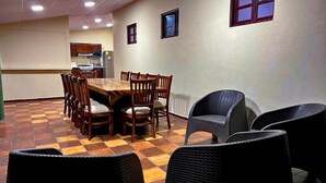 A dining area with a wooden table and chairs, a kitchen in the background, and a checkered floor. - Quinta Hojas de Mar - Las Hojas Beach (La paz)