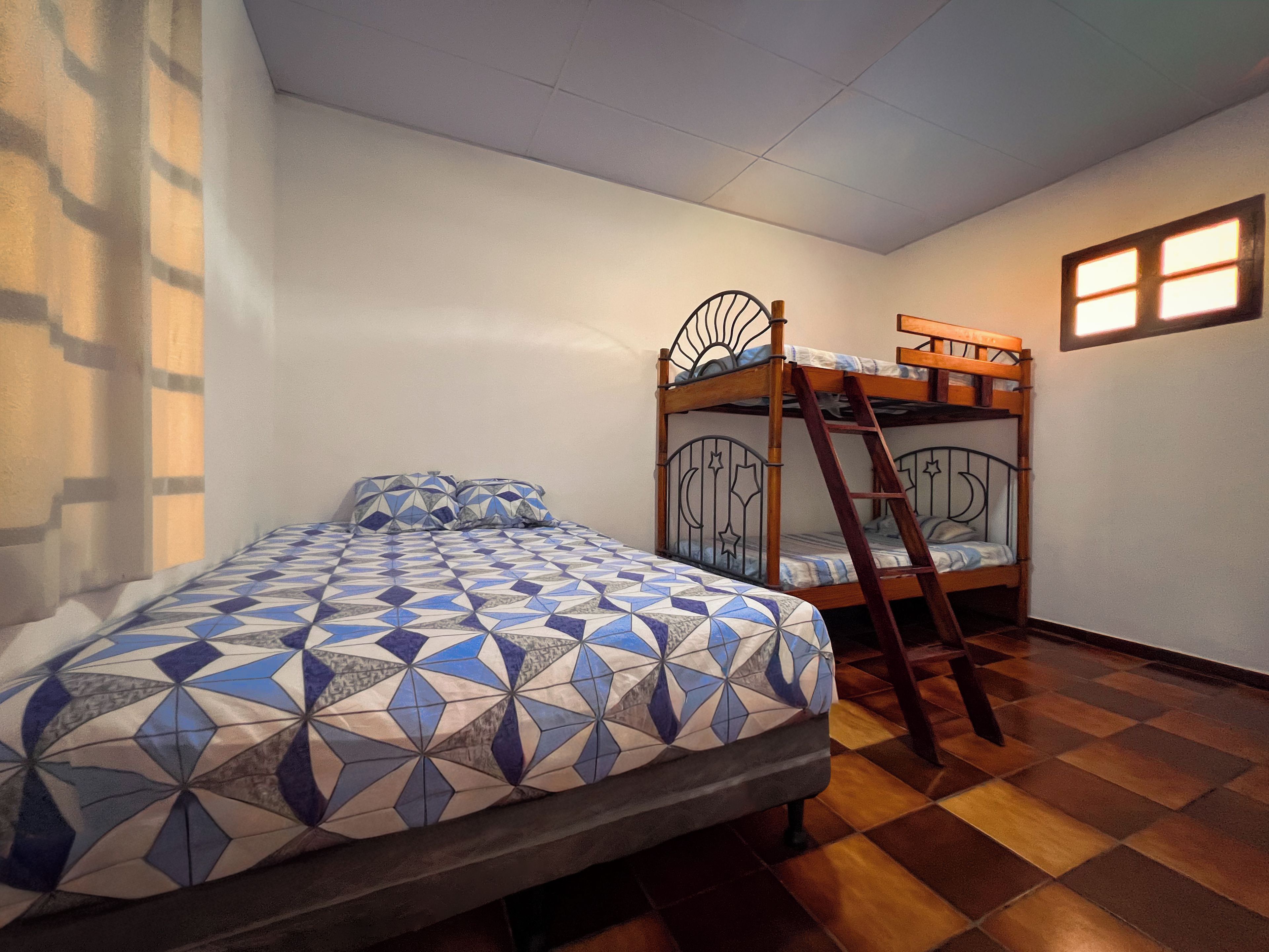Una habitación con literas, una cama individual y una ventana.