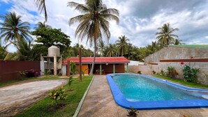 A swimming pool with a red-roofed building in the background, surrounded by palm trees and a clear sky. - Quinta Hojas de Mar - Las Hojas Beach (La paz)